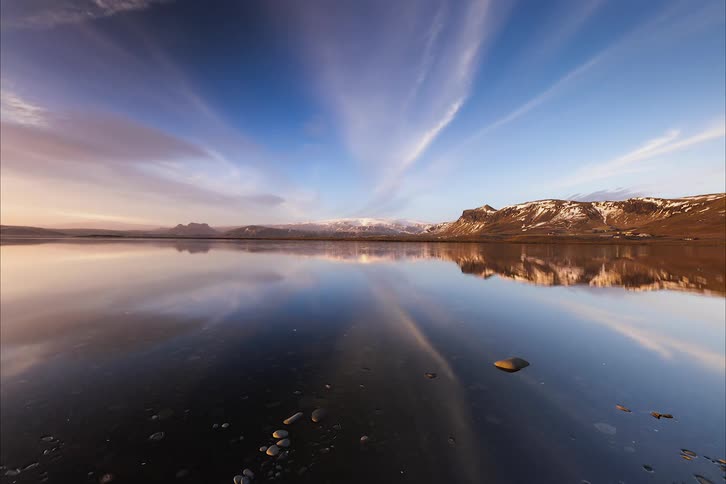 Blue sky and floating clouds are reflected on body of water