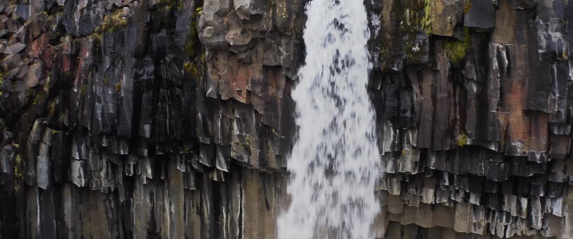 The waterfall pours off the cliff