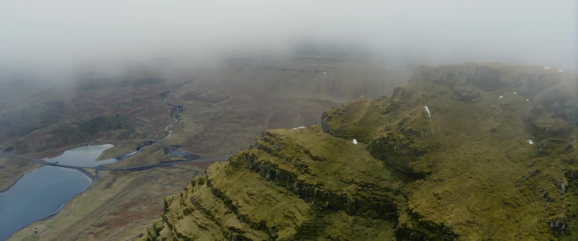An aerial view of a mountain mountainside on a foggy winter day