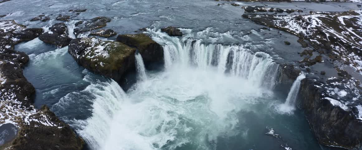 Camera slowly turns over a high aerial shot of a large waterfall
