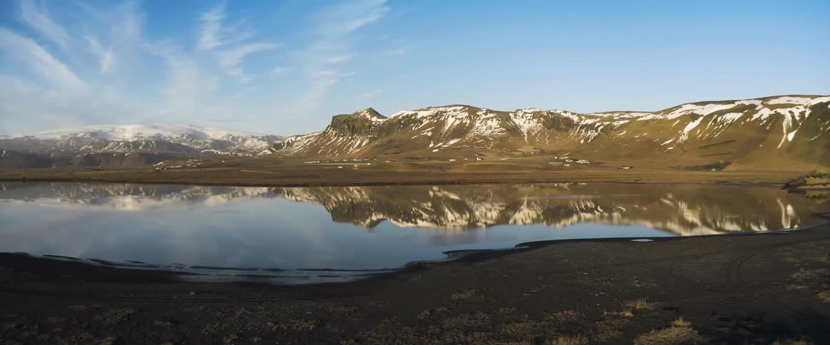 A calm lake next to a snowy mountain in nature
