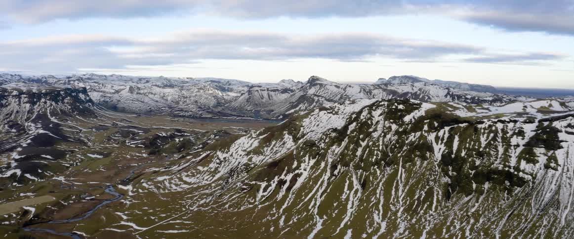 Aerial view of the snow covered peaks and slopes of a mountain range at evening