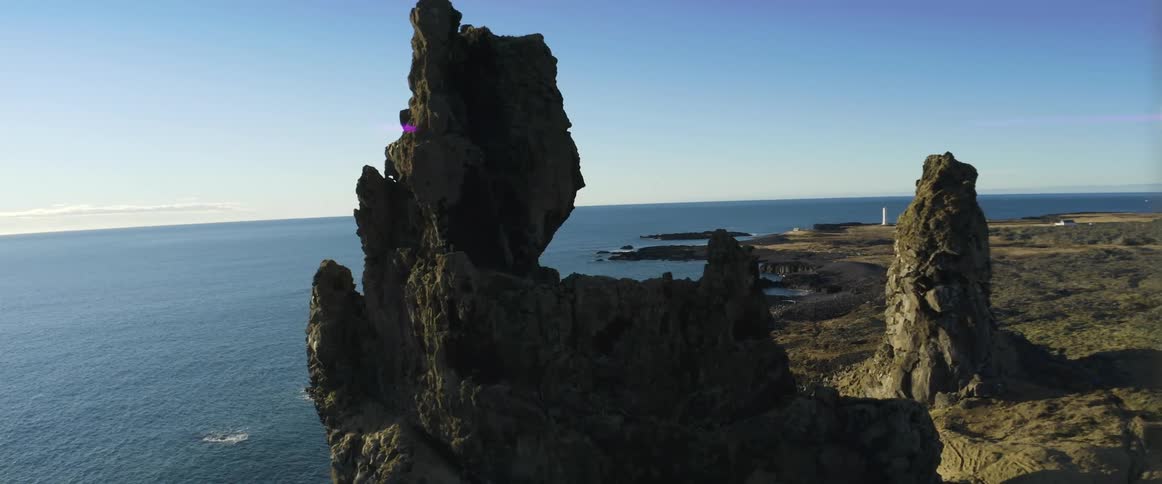 Aerial view of natural rock columns on the coast next to the ocean at evening