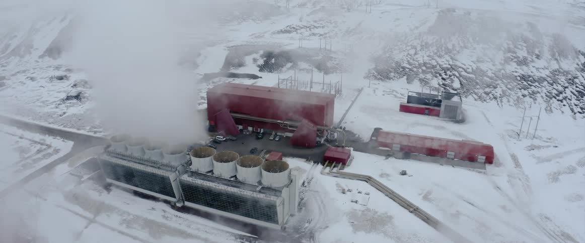 A red building and reactors with pipes in a rural area in the snow