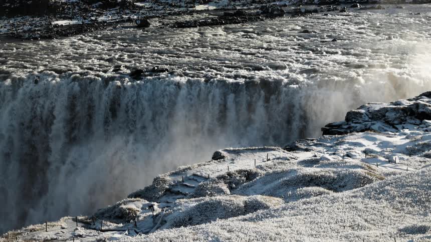 Water flowing and rushing down a waterfall with snow dusted banks