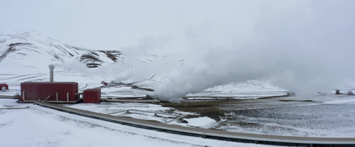 Camera pans around a plant or factory with smoke rising from it