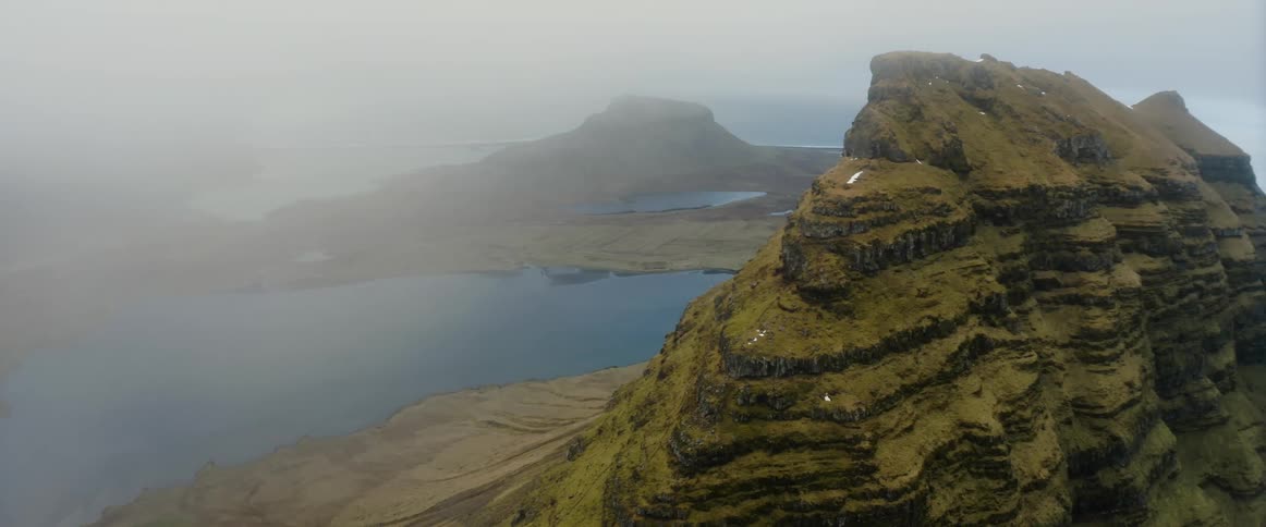 Camera pans past a mountain over the water