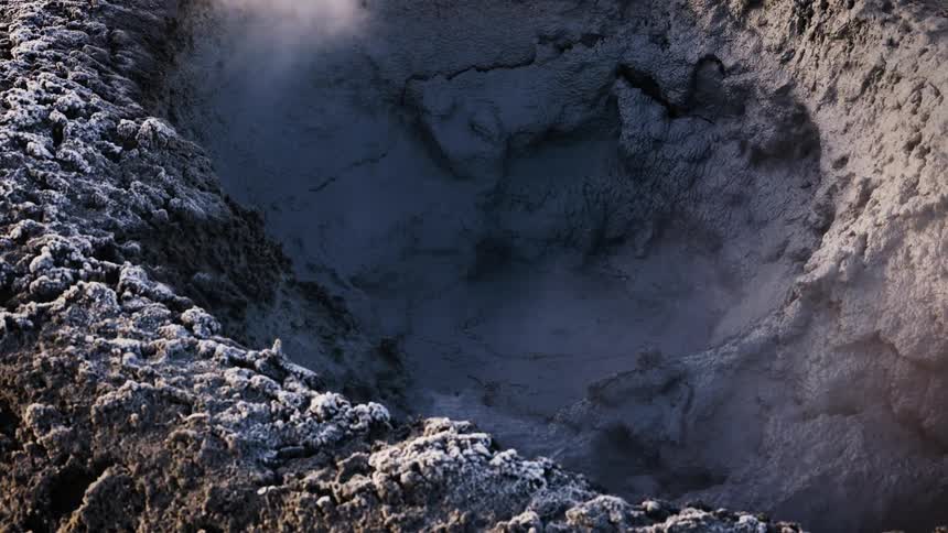 Hot mud in thermal pool bubbles as steaming vapor rises