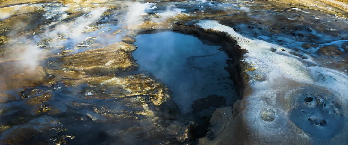 Steam rises up from hot springs in the ground