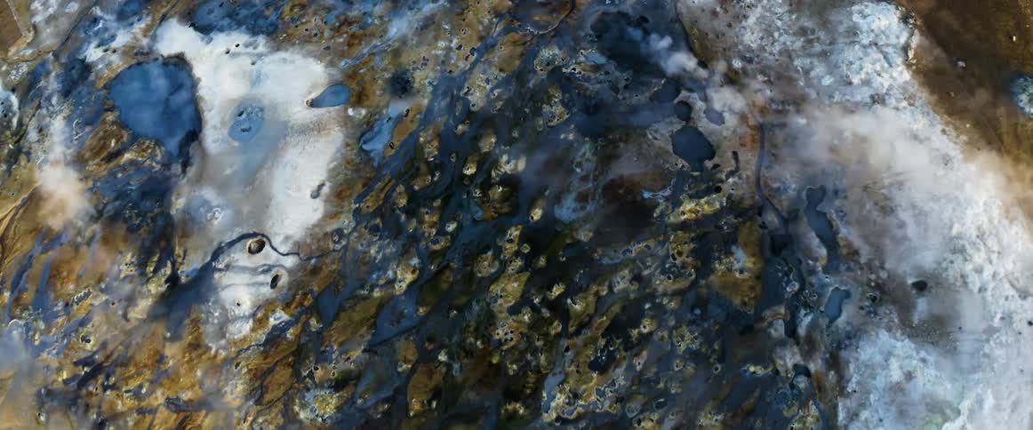 An aerial view of steam rising from geysers and the earth in nature