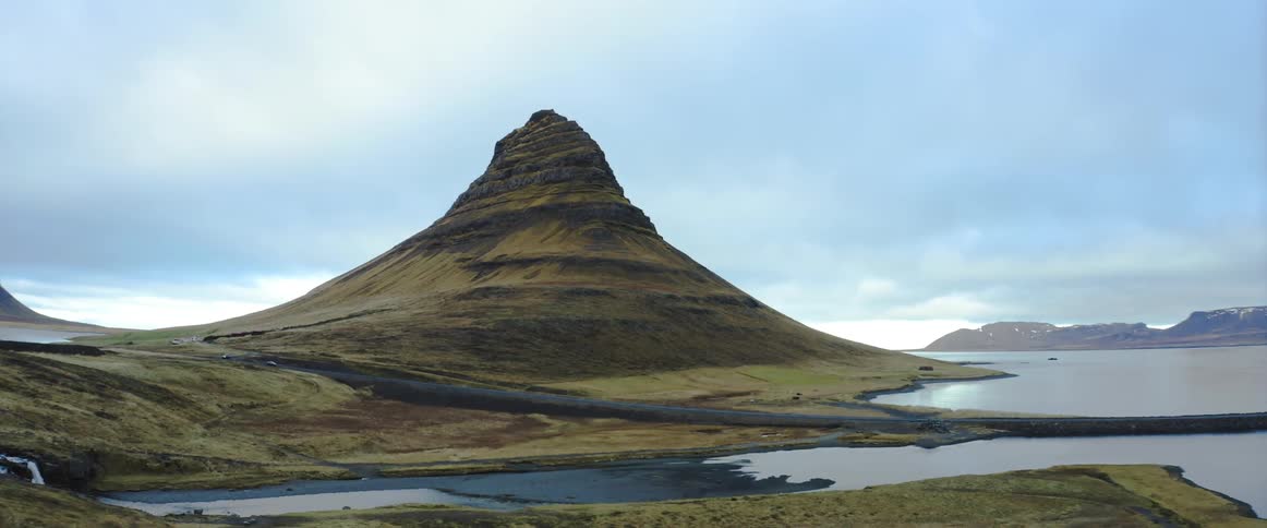 Aerial view of a solitary mountain peak towering over the terrain near the coast