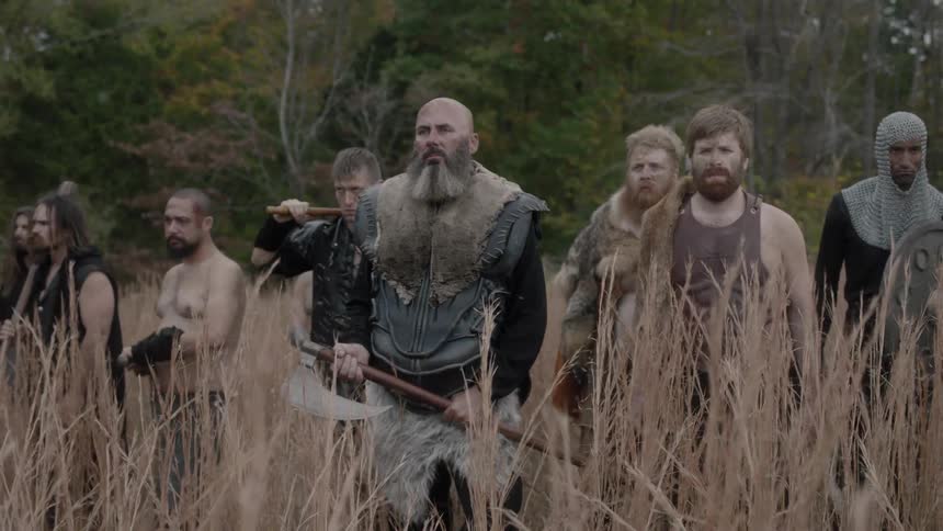 A group of warriors stand in a field of tall grass