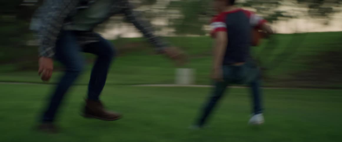 Father and son playing football on a public park at evening