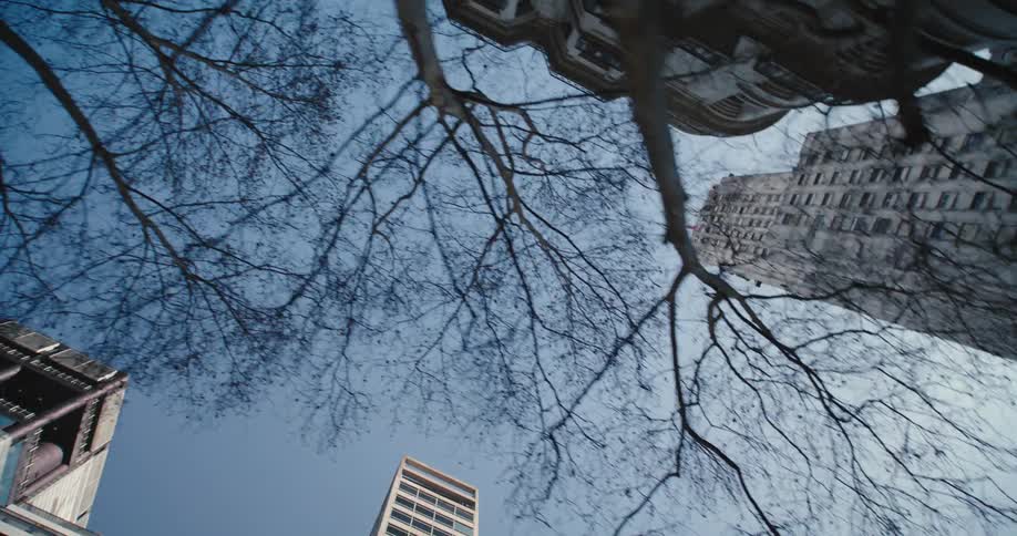 Camera tracks down a city street pointing straight up