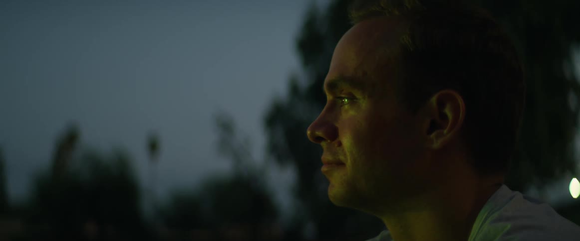 Different colored lights brighten face of man outdoors