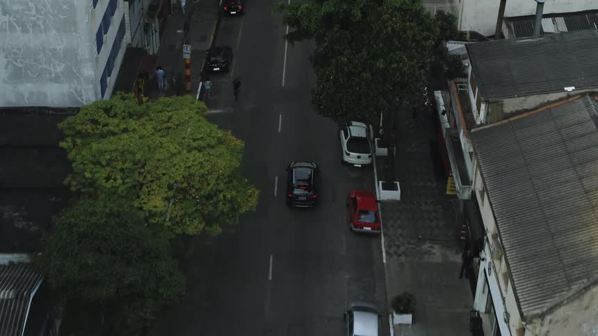 Car driving along street comes to a stop at an intersection as pedestrians enter the crosswalk