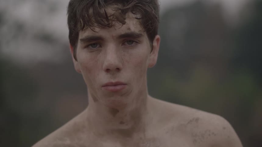 A young, bare-chested man opening his eyes