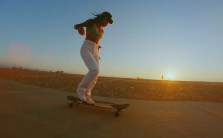 Young woman skateboards down a beach sidewalk