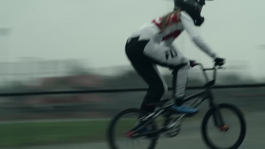 Female pedals dirt bike along hilly course