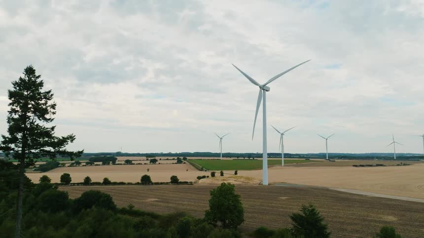 Wind turbines spin on a wind farm under a cloudy sky