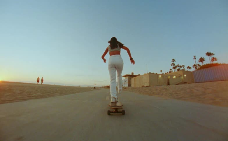 A teenage girl pushes with her foot as she rides her skateboard on a road