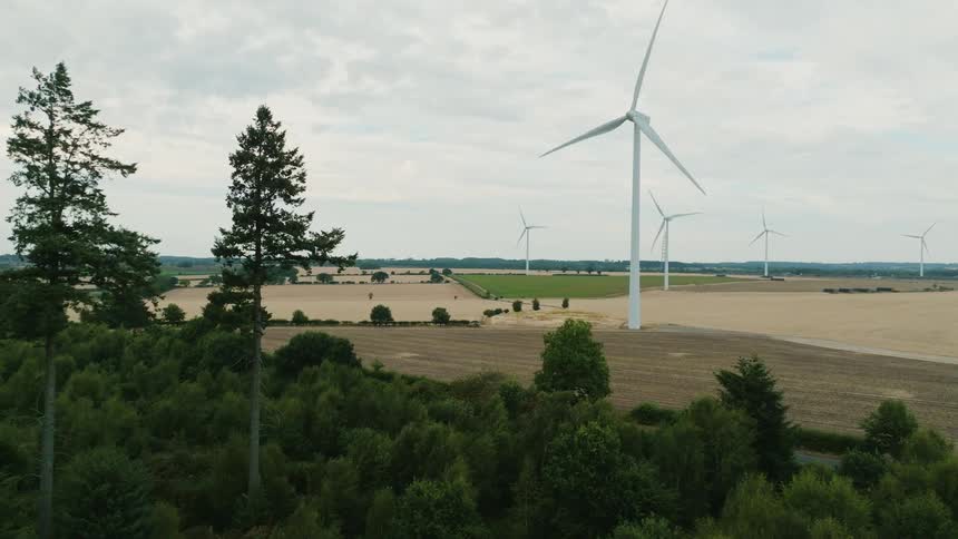 Smooth drone shot of turbines rotating slowly in a windfarm