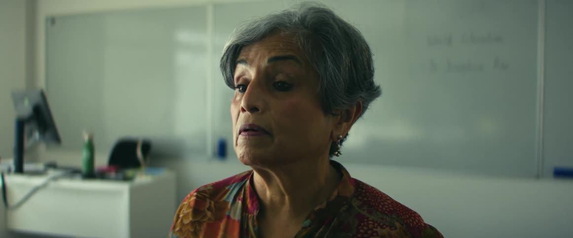 Female teacher standing in the middle of the classroom with a thoughtful and introspective facial expression