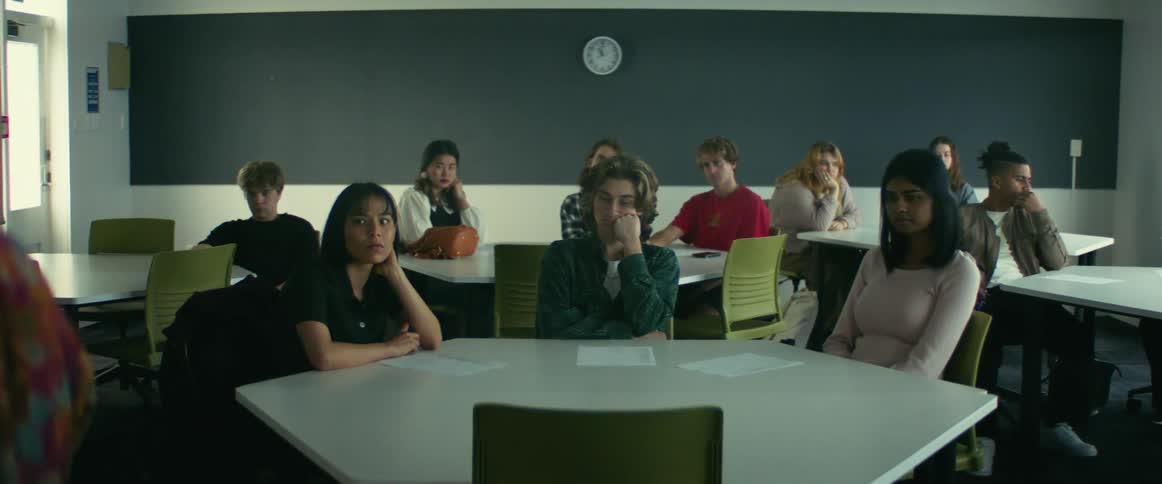 University teacher giving a lecture in front of students sitting on chairs in a classroom