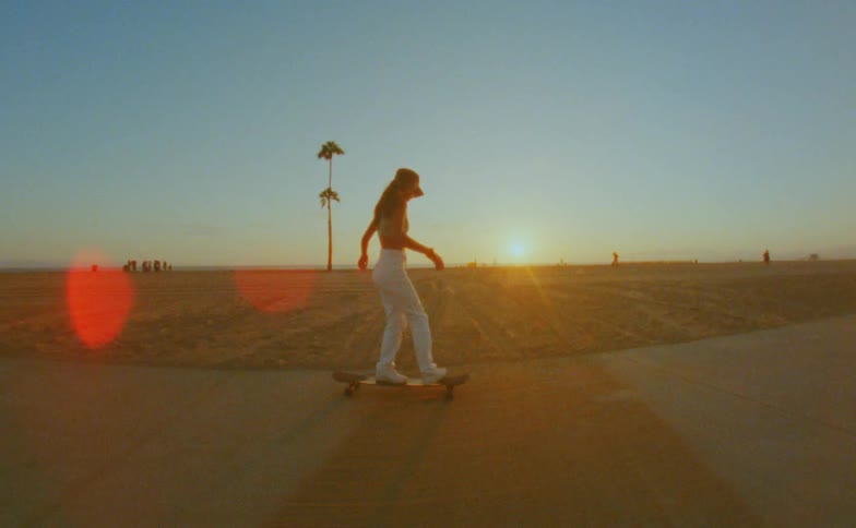 Woman skateboards down a road near a beach