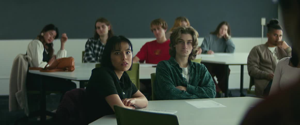 A groups of students sit in a classroom while listening attentively to their instructor