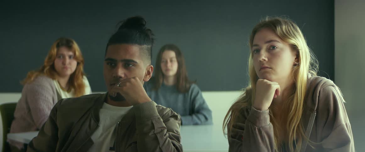 College students sitting at desks listen to professor giving lecture in class