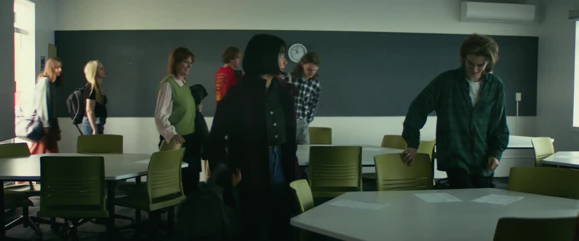A group of students walk into a classroom while the teacher awaits
