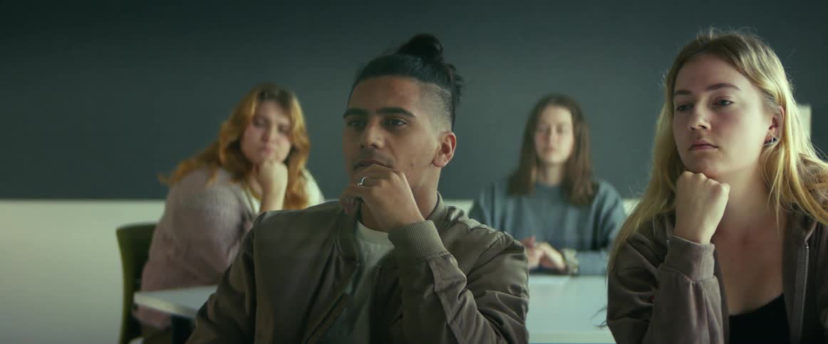 University students sitting on chairs in the classroom listening to the teacher