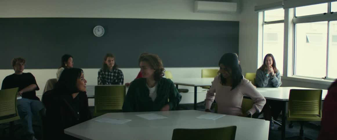 Students seated at a table talk to each other