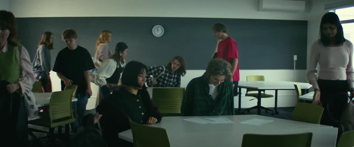 A group of students enter a university classroom and take their seats before class starts