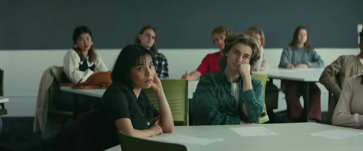 College students sitting at desks listen to professor giving lecture in classroom