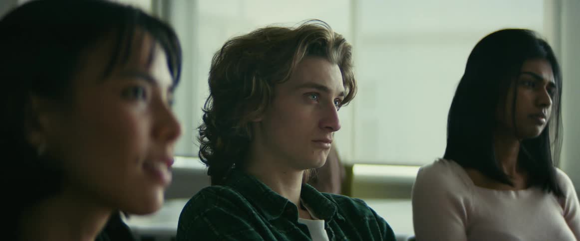 Camera pans closer to a male student as he smiles to himself