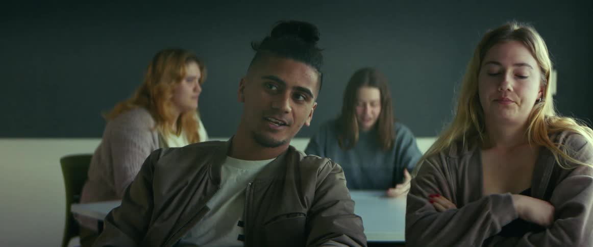 University student sitting on a chair in the classroom talking to a classmate
