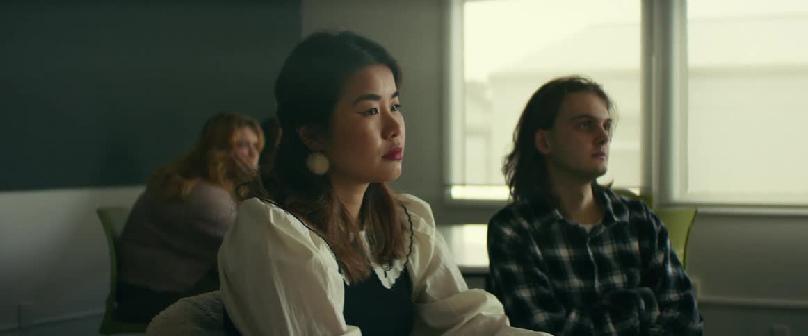 Camera slowly tracks to the right past a female student listening to a lecture