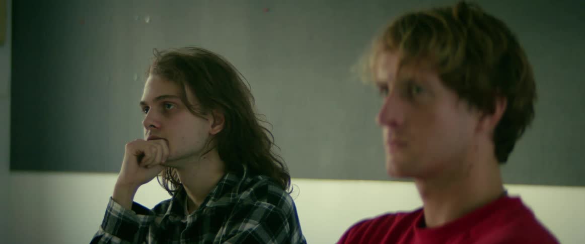 Two men are sitting in a room staring straight ahead