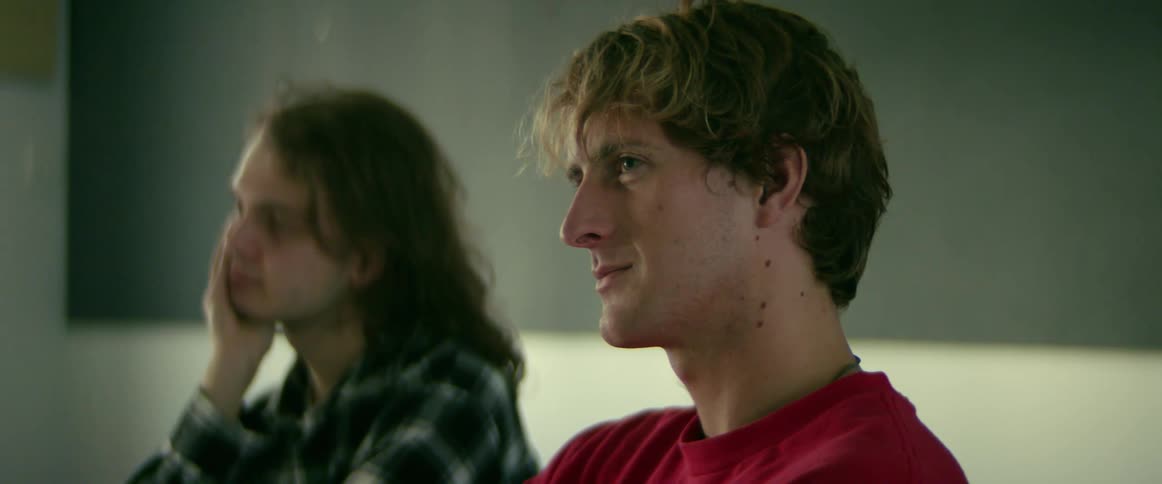 Camera slowly passes by a male student as he smiles