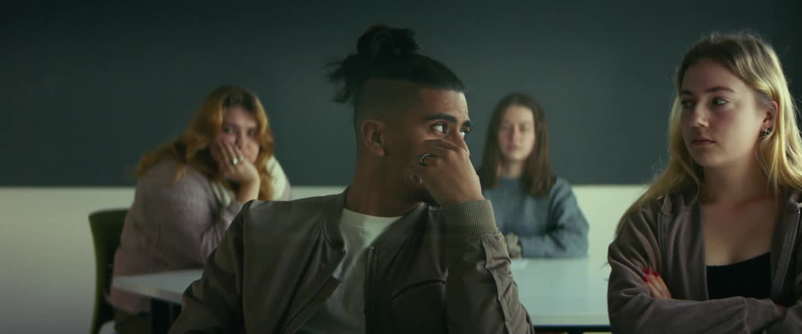 University student sitting on a chair in the classroom talking to a classmate