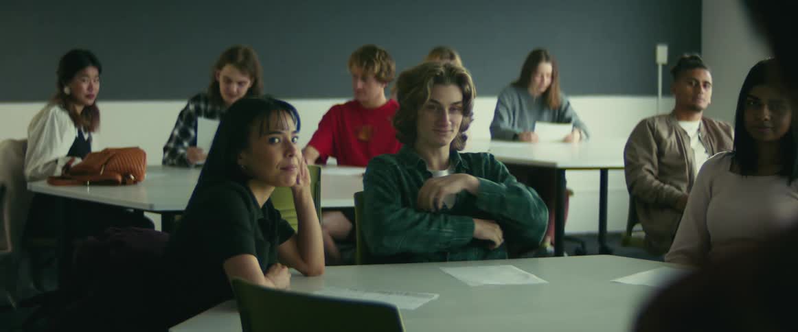 College students sitting at desks smirking professor talking in class