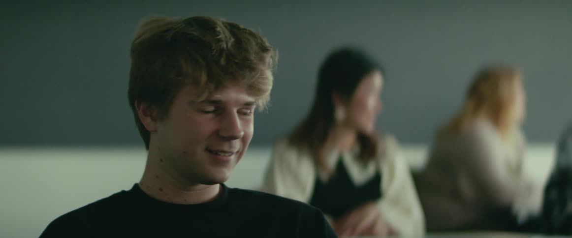 A young man smiles as he talks to classmates