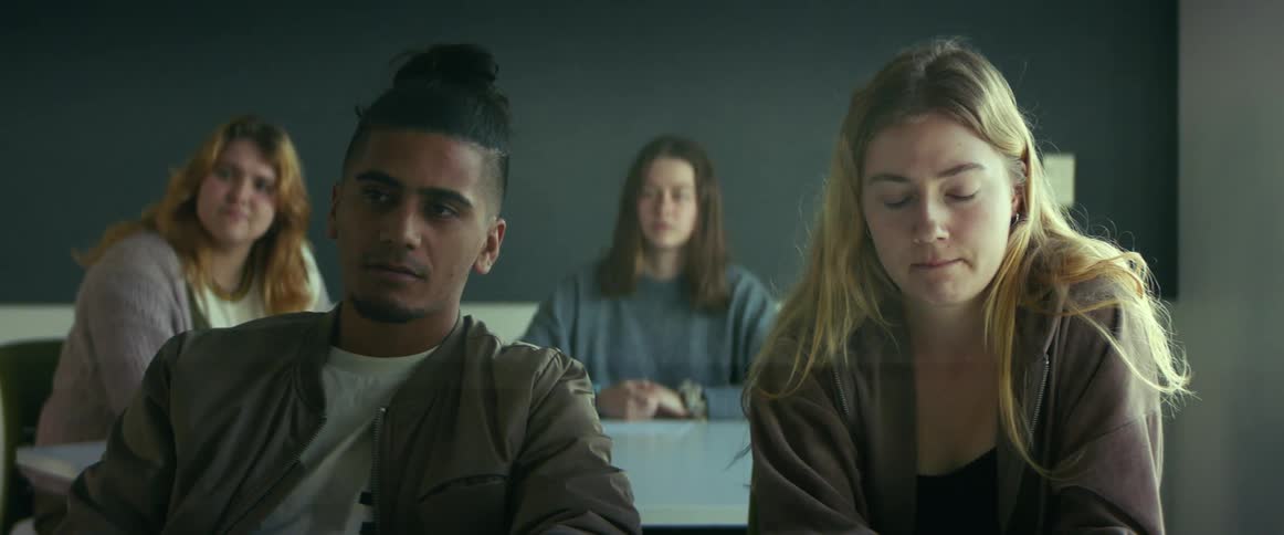 College students sitting at desks listen to professor giving lecture in class