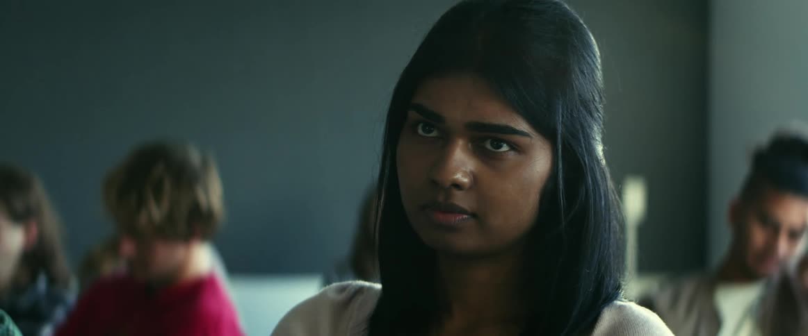 A young woman sighs looking bored while sitting in class