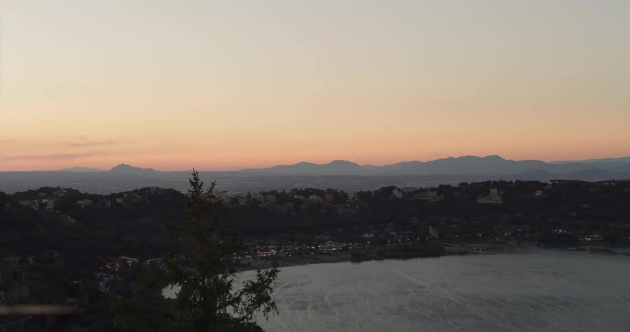 Small coastal town on the slopes of a hill next to the ocean at evening