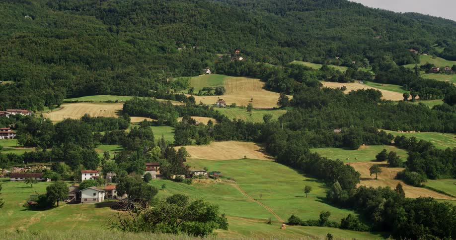 Small buildings on the farm fields at the gentle slopes of a mountain at morning