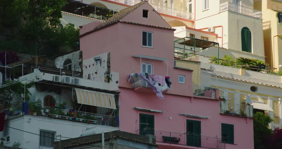 Drying clothes waving in the wind on the balcony of a pink house on a small town in the hills