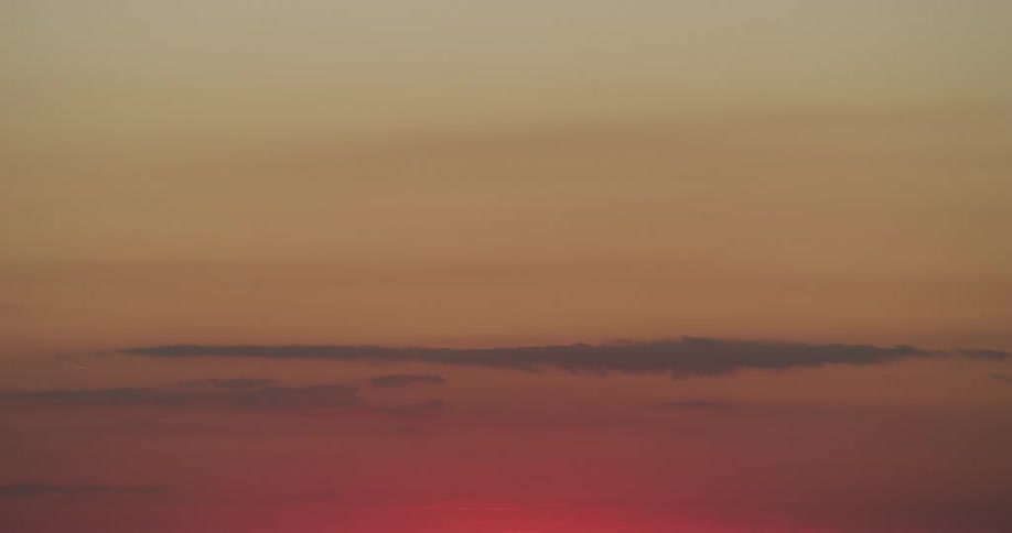 Clouds slowly float past a sunset in the sky